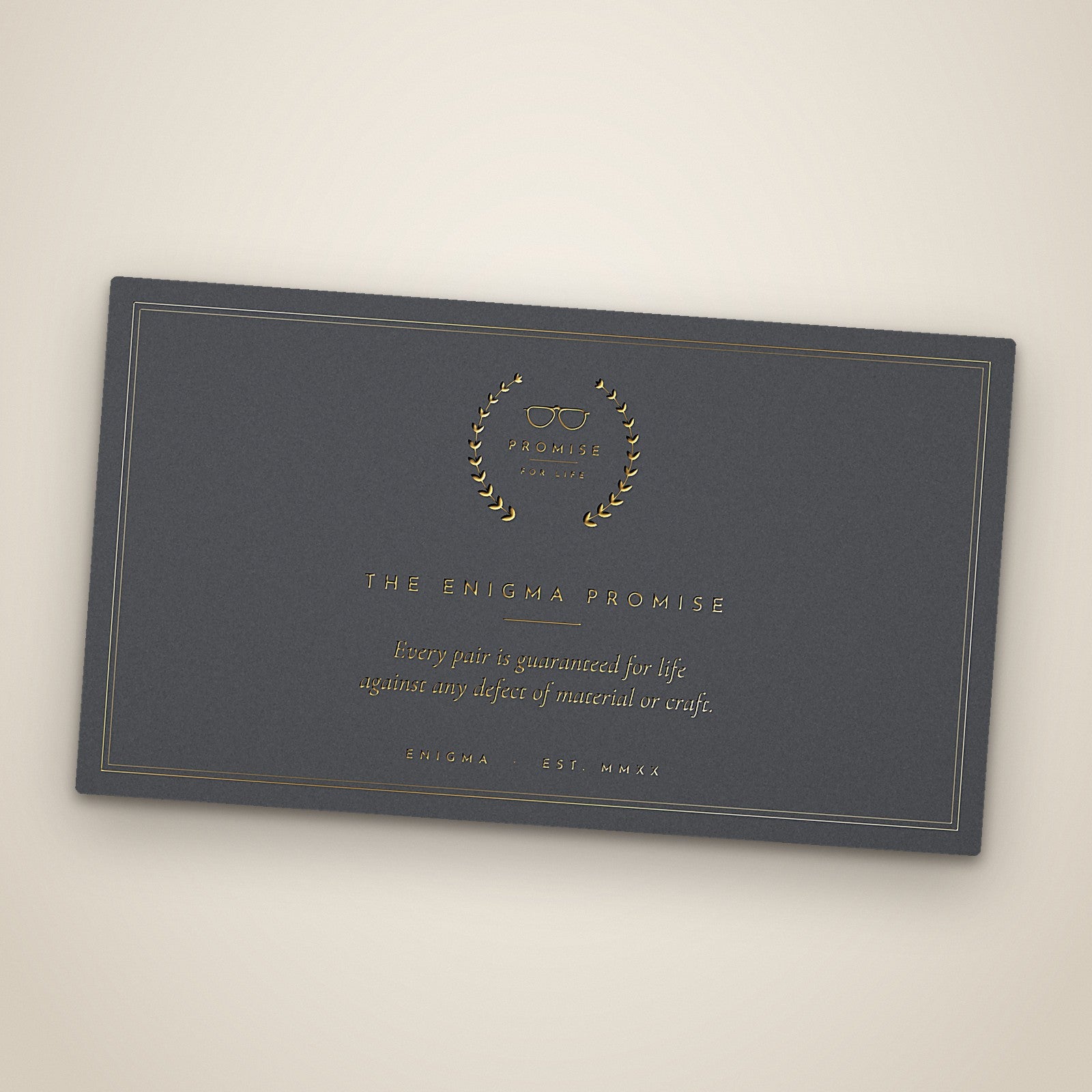 The ENIGMA Promise card, foil-stamped in gold beneath the laurel seal